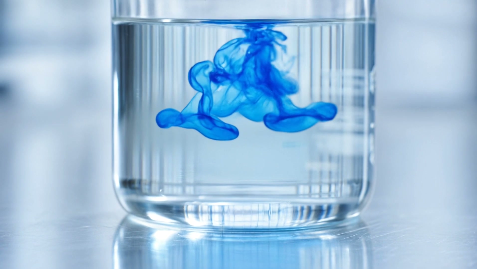 Concentrado azul disuelto en agua dentro de un vaso de laboratorio
